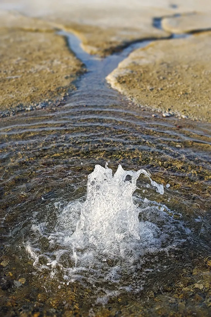 Agua brotando del terreno tras un sondeo en el campo